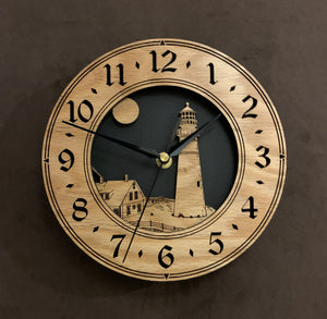 Round oak clock with a lighthouse, moon and lightkeeper's house lasered in the face against a black background - larger sizes