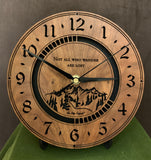 Round walnut clock with a mountain and the words, "Not all who wander are lost" lasered in the face - 8" on easel