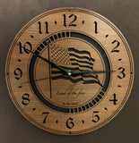 Larger sizes of the round Walnut clock with a laser-cut flag in the middle, the words, "Land of the Free" beneath it, surrounded by a circular cut-out band showing the black background, and the numbers 1-12 cut through around the perimeter.