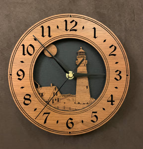 Round walnut clock with a lighthouse, moon and lightkeeper's house lasered in the face against a black background - larger sizes