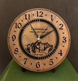 Round walnut clock with a mountain and the words, "The mountains are calling and I must go" lasered in the face - 8" on easel