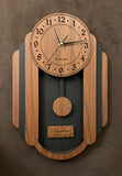 Oblong walnut and black pendulum clock consisting of a round face and, under it to either side, 3 alternating walnut and black rounded segments which decrease in size from front to back. The clock has a rounded bottom and a black background beneath the face. Front view, larger sizes