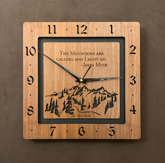 A square walnut clock with the numbers on the outer square section, while on the inner square section a mountain and the words, 