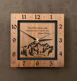 A square walnut clock with the numbers on the outer square section, while on the inner square section a mountain and the words, "The Mountains are calling and I must go. -John Muir" are lasered in the wood. The concentric wood squares have a gap between them and are against a black background. 8" Size