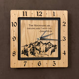 A square oak clock with the numbers on the outer square section, while on the inner square section a mountain and the words, "The Mountains are calling and I must go. -John Muir" are lasered in the wood. The concentric wood squares have a gap between them and are against a black background. Larger Sizes