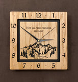 A square oak clock with the numbers on the outer square section, while on the inner square section a mountain and the words, "Not All Who Wander Are Lost" are lasered in the wood. The concentric wood squares have a gap between them and are against a black background. Larger Sizes