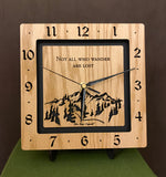 A square oak clock with the numbers on the outer square section, while on the inner square section a mountain and the words, "Not All Who Wander Are Lost" are lasered in the wood. The concentric wood squares have a gap between them and are against a black background. 8" Size on easel