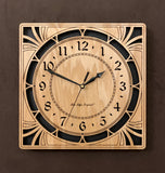 A square oak clock with cutouts forming a patterned circle around the face and numbers of the clock and cutout flourishes in the corners. Somewhat in an Art Deco style. 10" Size