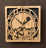 An oak square clock with two concentric  circles on front with the numbers 1-12, the second level shows a cutout mountain with a moon above, all set against a black background. 8" Size 