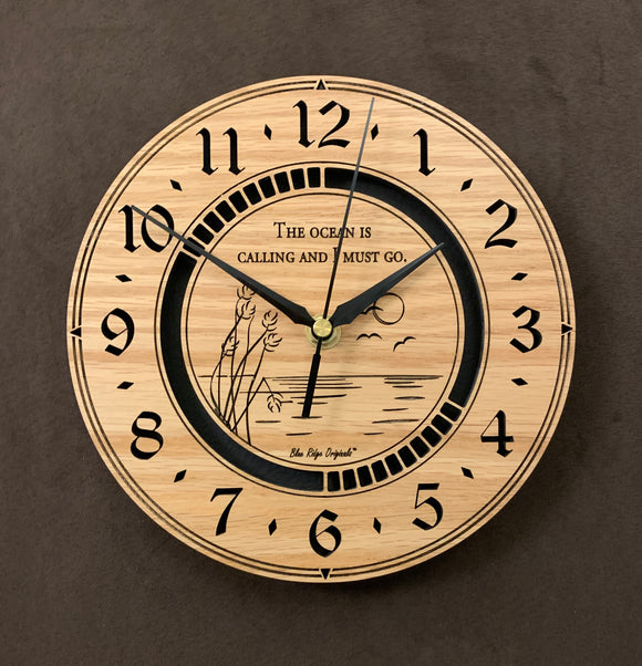 Round oak clock with an ocean scene of sun, birds and ripples in the water along with the words, 