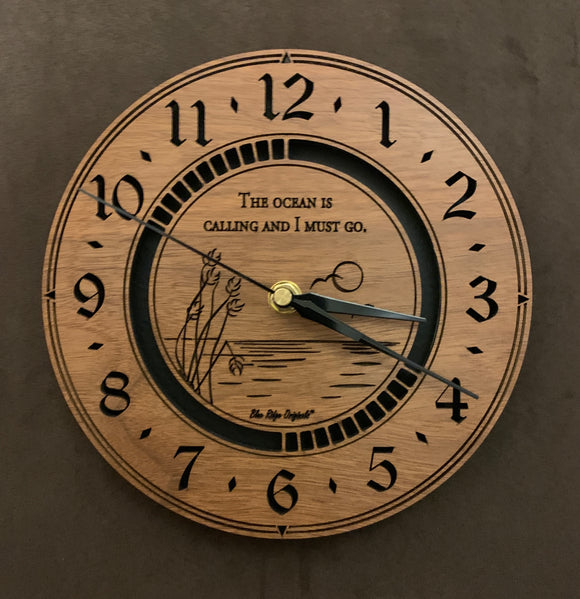 Round walnut clock with an ocean scene of sun, birds and ripples in the water along with the words, 